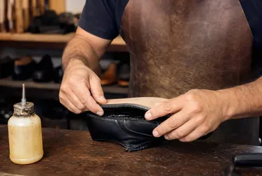 Sapateiro aplicando cola na sola de um calçado em um ambiente profissional.